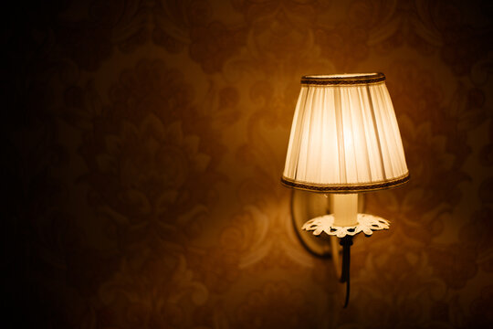 Lantern with flame in retro style on the background of a stone wall of an ancient house.