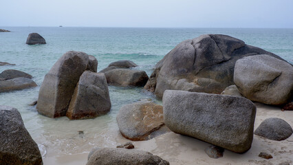 A group of natural granite boulders scattered on the shoreline of Siangau Beach, Bangka Island, Indonesia