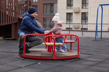 Father and daughter playing on a carousel, bonding and having fun