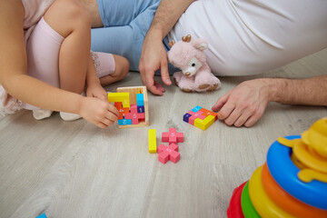 close-up of father and daughter sitting on floor at home, bonding while playing with colorful toys