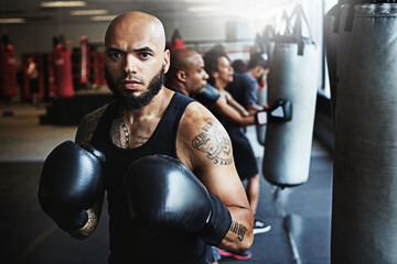 Boxing class, man and portrait at punching bag for fitness training, gym practice and fight workout. People, pro boxer and serious at health club for conditioning, match preparation and combat sport