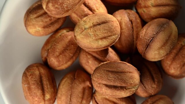 Extreme close-up of a single walnut-shaped cookie rotating. Focus on the intricate texture mimicking a real walnut shell and the "seam" detail. Hypnotic food art.