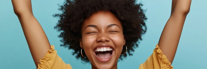 A young woman with curly hair is smiling and laughing, her arms raised in a joyous gesture.