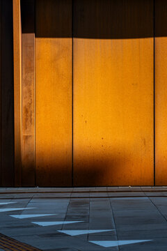 Modern architecture wall with orange metal texture in light and shadow creating minimal geometry for contemporary exterior surface design