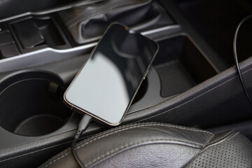 Mobile phone with charging cable in car, closeup