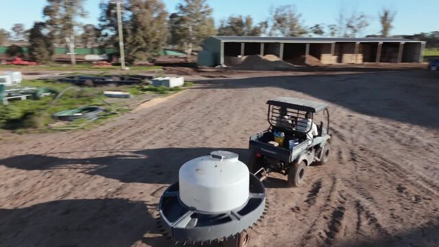 4K cinematic Drone shot of a farm utility vehicle towing a milk tank across a muddy cattle yard