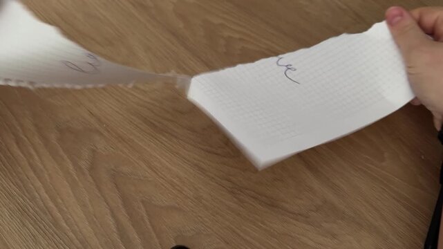 Hands Tearing Paper Sheet on Wooden Table Surface