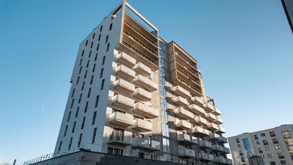 Modern residential high-rise with repeating balconies and glass facade under clear blue sky — contemporary urban architecture and real-estate development exterior © Serhii