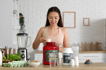 Sporty young happy Asian woman making protein shake at home