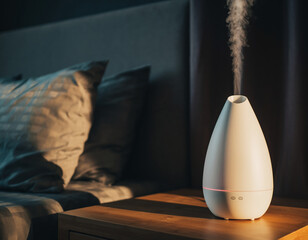 White aroma oil diffuser emitting mist in bedroom