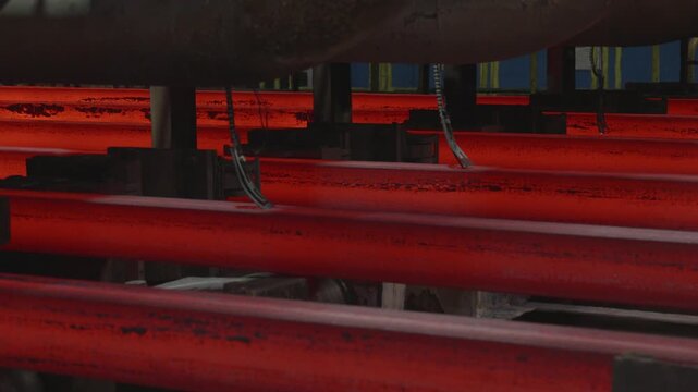Glowing hot steel billets moving through foundry production line