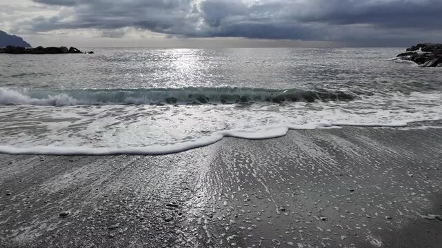 soft waves roll onto sandy beach in winter coastal village bogliasco in slow motion 120fps
