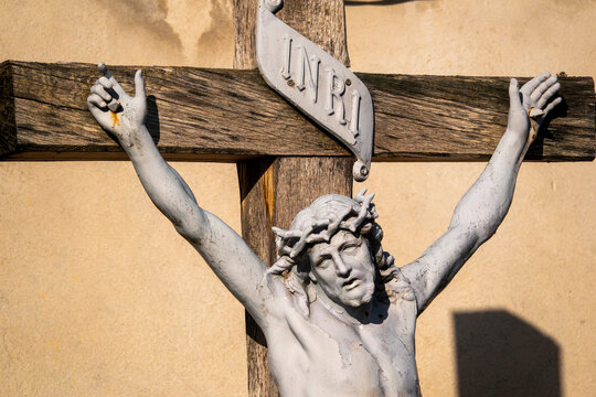 Outdoor crucifix detail with INRI plaque, warm sunlight highlighting Christ on the cross.