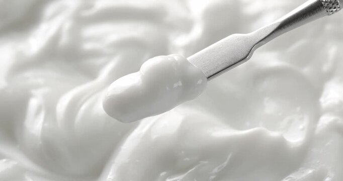 Cosmetic spatula with moisturizing cream on cream texture background.