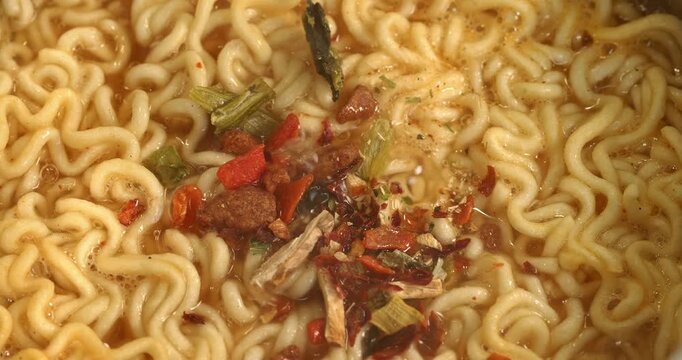 Spices are added to boiling water with instant noodles, the process of making Korean spicy  ramyong soup.