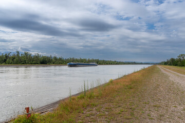 Cargo ship navigating river canal with towpath
