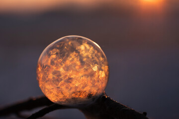 Zamarznięta bańka mydlana z kryształkami lodu, zimowa abstrakcja w ciepłym świetle