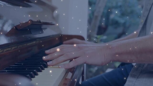 Mature pianist placing hands on keys performing melodies for music with light particles shimmering