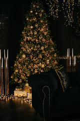 Background for a photo shoot: a Christmas tree decorated with toys surrounded by furniture in a dark studio