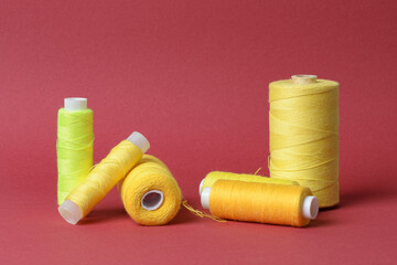 Many spools with yellow thread on red background