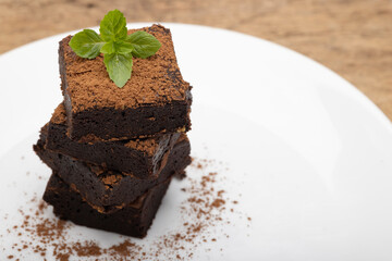 Chocolate brownies with pepper mint leaf on top on white plate background © Suttiwan