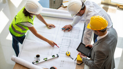 Three construction workers reviewing blueprints on a table