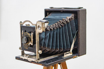 Antique large-format brassnickel-plated steel camera on a wooden tripod, showcasing dials, knobs, and bellows Glass plate holder visible inside the open back Soft, even lighting in minimal backgro