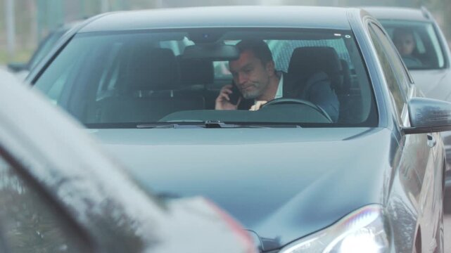 Anxious man driving in traffic, Anxious executive focuses on steering wheel amid rush hour traffic congestion