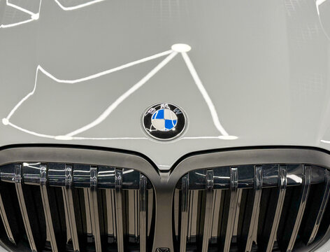 BMW logo on metallic gray car. Hood and black kidney grille. Emblem of BMW on hood of gray car close-up. Gray BMW X7 G07 M60i logo on car hood. German premium SUV car. 