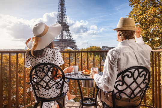 Rear view of a romantic couple enjoying breakfast on a balcony with view of the Eiffel Tower in Paris, France
