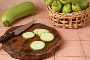 Wooden board with slices of raw zucchini on table