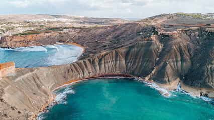 Breathtaking aerial shot of Ghajn Tuffieha's turquoise waters and rugged clay cliffs in Malta. Perfect for Mediterranean travel brochures, tourism ads, and social media content. © JULIA