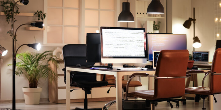Programmer's workplace with computer monitors in office at night