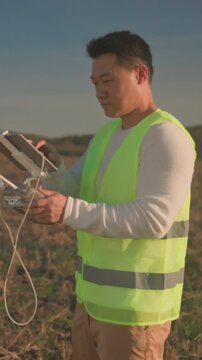 Field specialist adjusts controls at sunset, Worker calibrates drone equipment during golden sunset on farmland