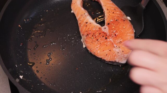 Person turning fish in a frying pan during prepare dinner. Cooking at home. High quality 4k footage
