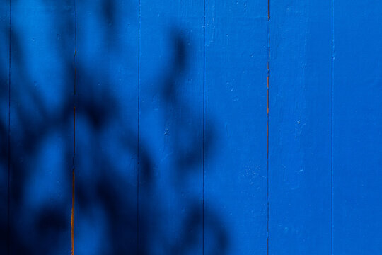 parete fatto da tavole di legno colorate di blu, coperte parziamente dal riflesso di alcune ombre leggere