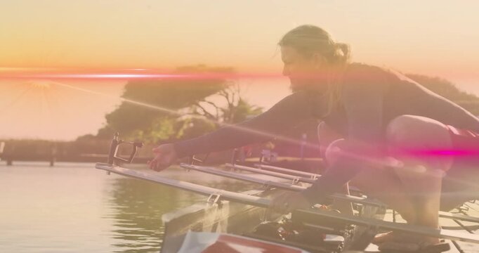 sun rising causing lens flare drifting frame as sports rower kneeling aligning oarlocks for rowing
