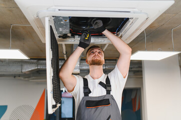 Hvac technician repairing ceiling air conditioner unit