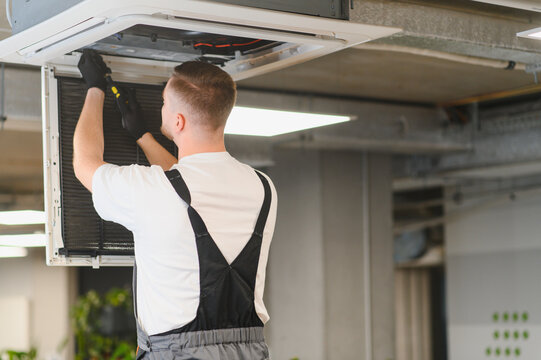 Hvac technician servicing commercial ceiling air conditioning unit