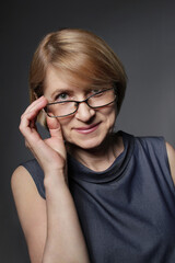 Fototapeta premium Senior woman 65 years old in glasses looking up with a sly smile. Caucasian mature female portrait. Confident businessperson and smart teacher.