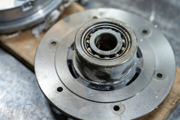 Vue sur une pi&egrave;ce m&eacute;canique et des composants m&eacute;talliques pos&eacute;s sur un &eacute;tabli dans un atelier industriel, illustrant un environnement de fabrication et d&rsquo;assemblage technique.