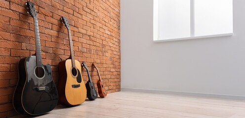 Different guitars near brick wall