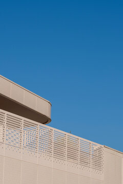 Modern architecture facade with perforated railing and roofline against blue sky showing minimal geometry and clean design detail today
