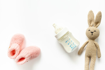 Baby food in a milk bottle and baby accessories - knitted bunny and booties, top view