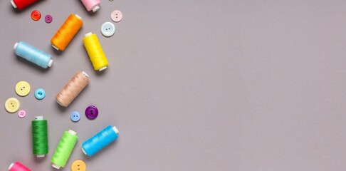 Different thread spools and buttons on grey background with space for text