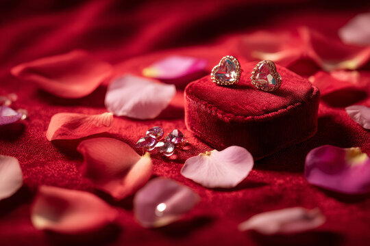 Heart-shaped jewelry on red velvet cushion surrounded by rose petals, shallow depth of field, luxurious Valentine product photography