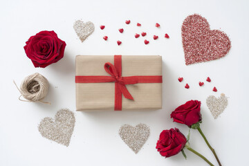 Valentine-themed gift wrapping flat lay with red ribbon, kraft paper, roses, and glitter hearts, minimal white background, artistic composition for greeting cards and e-commerce visuals