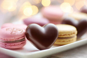 Valentine's dessert arrangement with heart-shaped chocolate, pastel macarons, soft lighting, shallow depth of field, elegant commercial stock photography