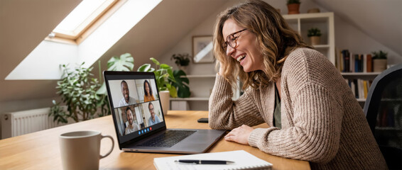 Woman attends a remote video meeting from her cozy home office, engaging with teammates on screen, reflecting modern hybrid work culture.