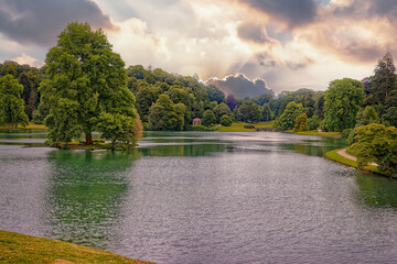 Sunset behind clouds over an English Park in summer with lakes and trees © John Gilham 